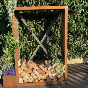 Wooden firewood storage with a crossbar against a green hedge
